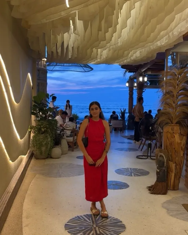 Jessica, the web designer behind Mindful Presence Studio, smiling in a red dress in a softly lit seaside walkway